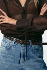 Pantalón de jean celeste de tiro alto, corte wide leg cropped, con cinco bolsillos y cinturón marrón con tachas.