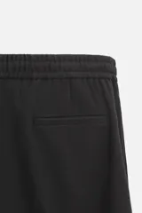 Pantalón color arena de corte recto, confeccionado en tejido elástico. Cuenta con cintura elástica ajustable con cordón, bolsillos laterales y bolsillos de vivo en la parte trasera.
