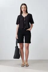 Blusa negra de broderie con escote en V y lazos para atar en el frente. Tiene mangas cortas con terminación de puntilla. 