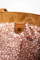 Bolso tipo tote de gamuza vegana color camel, con asas de mano y logo grabado en el frente.