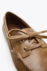 Zapato plano estilo náutico color marrón claro, con detalle fruncido en la parte delantera, suela a contraste y cierre mediante cordones.