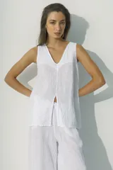 Blusa blanca sin mangas con escote en V y abertura frontal.