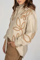 Sobrecamisa negra con estampado de hojas blancas, cuello camisero, cierre frontal con botones y mangas largas.