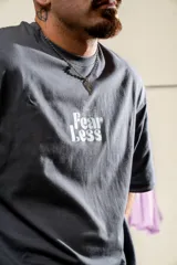 Remera gris con estampado en el frente con la frase "Fear Less". En la espalda tiene un estampado vertical con la frase "More Strength".