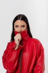 Chaqueta bomber de cuero color marrón, con cuello de piel sintética roja, cierre frontal con cremallera y bolsillos laterales.