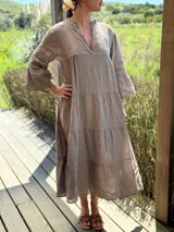 Vestido midi color gris topo de lino, con cuello mao, escote en V, manga francesa acampanada y corte escalonado con volados.