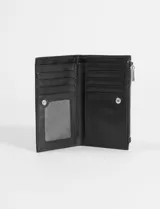 Billetera pequeña de cuero sintético texturizado color verde azulado, con cierre superior de cremallera y un pequeño logo metálico en la parte frontal inferior derecha.