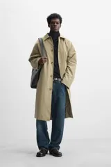 Gabardina color beige de corte amplio, con cuello solapa, manga larga, bolsillos laterales con solapa y cierre frontal con botones.