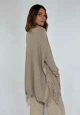 Sweater tostado de punto con cuello alto, corte holgado, bolsillo frontal y detalle de flecos en el lateral.