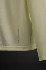 Camiseta deportiva de manga larga color amarillo pálido, confeccionada en tejido técnico perforado, ligero y elástico.