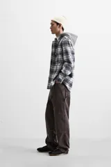 Sobrecamisa relaxed fit de algodón a cuadros azul marino y blanco, con capucha gris combinada a contraste, manga larga con puños abotonados, bolsillos plastrón en el pecho, bolsillos laterales en la cadera y cierre frontal con botones.