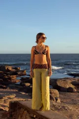 Pantalón de lino color amarillo, de corte ancho y tiro medio. Presenta detalles de estampa con motivos geométricos en la cintura y laterales.