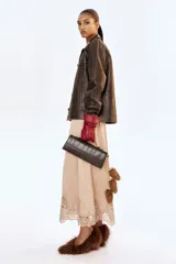 Cartera rectangular color marrón oscuro con efecto de piel de cocodrilo. Cuenta con un asa superior, solapa con cierre magnético oculto y una correa fina ajustable para llevar al hombro o cruzada. Interior forrado.