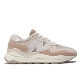 Championes New Balance modelo 57/40, color beige y rosa pálido, con detalles en gris claro. Presentan una silueta aerodinámica con una entresuela sobredimensionada inspirada en el modelo 574 clásico y elementos de diseño de los años 80 y 90. La parte superior combina gamuza y malla.