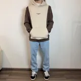 Canguro con capucha color marrón y beige, con logo bordado en el pecho y bolsillo tipo canguro.