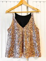 Musculosa dorada con lentejuelas y tirantes finos.