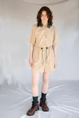 Vestido corto color beige de microfibra con cuello verde a cuadros, mangas cortas, cintura elastizada con cordón ajustable y cierre frontal con botones.