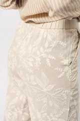 Pantalón de corte recto color marrón con bordado floral blanco.