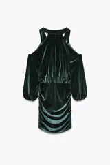 Vestido corto de terciopelo verde esmeralda, con escote fluido, mangas largas abullonadas y aberturas en los hombros.