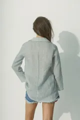 Camisa a rayas verticales blancas y negras, de corte recto y mangas largas.