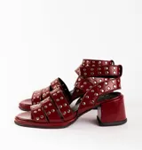 Sandalias de cuero color bordó con tres tiras horizontales sobre el empeine y pulsera al tobillo, ambas con apliques de tachas plateadas.