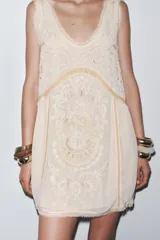 Vestido corto color crudo con bordados a tono, escote redondo y sisas amplias.