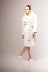 Bata larga color crema confeccionada en pana, forrada en corderito con puntilla de algodón en la solapa y puños. Tiene lazo de pana para ajustar en la cintura y bolsillos laterales.