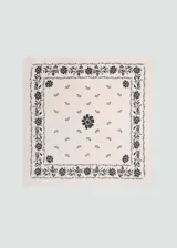 Pañuelo cuadrado de algodón color crema con estampado de flores negras. Tiene un borde con un patrón floral y un diseño floral más pequeño en el centro.