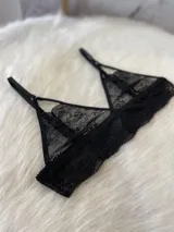 Conjunto de lencería negro de encaje elastizado, compuesto por un corpiño triangular, una tanga regulable y un portaligas con ligas incluidas.