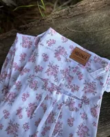 Pantalón de jogging blanco con estampado floral en tonos rosados, corte holgado y puños elásticos.