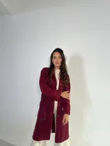 Tapado largo de jeans color bordó con cuello camisero, cierre frontal con botones a presión, mangas largas con puños abotonados, bolsillos laterales y bordado floral en la espalda.