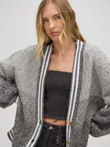 Cardigan tejido de punto con patrón de rombos en degradé de grises y blanco. Tiene corte oversize, mangas largas y cierre frontal con botones.