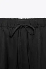 Pantalón jogger color gris claro, de tiro alto con cintura elástica ajustable con cordones, bolsillos delanteros y traseros con solapa, y puños elásticos en el bajo.