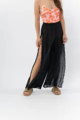 Pantalón blanco de gasa liviana con cintura elástica y aberturas laterales con detalle de pompones.