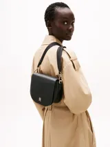 Cartera saddle negra de Tommy Hilfiger con correa de textil trenzado ajustable y extraíble, cierre de solapa magnético, bolsillo interior con cremallera e insignia del monograma TH en la parte delantera.