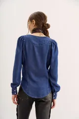 Camisa azul de tencel con calce entallado, cuello redondo, mangas largas con frunces en los hombros y costuras a contratono.