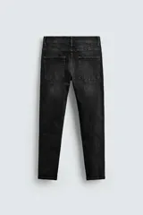 Pantalón de jean azul oscuro con efecto lavado y roturas en las rodillas, de corte ajustado al cuerpo desde la cintura hasta el tobillo.