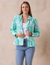 Campera blanca con bordado floral en verde agua, cuello solapa, cierre con botones, bolsillos delanteros y ruedo fruncido.