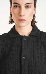 Camisa negra de manga corta con textura y cuello clásico.
