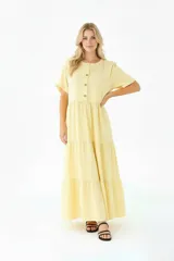 Vestido largo amarillo de lino, corte recto, con cuello mao, mangas cortas y cierre frontal con botones.