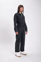 Mono de jean negro con cuello camisero, cierre frontal con botones y bolsillos en el pecho y laterales.