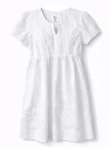 Vestido corto de broderie color blanco, con escote en V, mangas cortas y bolsillos laterales. Presenta un diseño con bordado calado floral y cintura elástica fruncida.