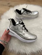 Zapatillas de diseño moderno en color plateado, con suela blanca y un look versátil.