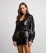 Campera bomber cropped de lentejuelas negras, con cuello tradicional, cierre delantero por cremallera y mangas largas.