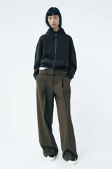 Pantalón de tiro medio color verde oliva, con cintura con trabillas, bolsillos laterales ocultos, cinturón ajustable con hebilla metálica, pinzas delanteras y cierre frontal con cremallera, botón y gancho metálico.