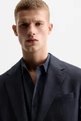 Blazer azul marino de lino, corte regular fit, con solapas de muesca, cierre de dos botones, bolsillo de vivo en el pecho, bolsillos de solapa en la cadera, aberturas en la espalda y puños con botones.