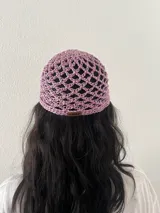 Gorro tipo casquete tejido a crochet con hilo satinado color lila. Tiene una etiqueta de cuero con el logo de la marca Chili.