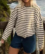 Buzo tejido a rayas horizontales rojas y blancas, con cuello tipo camisa y abotonadura frontal.