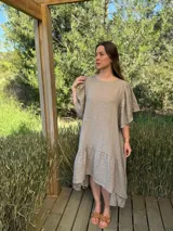 Vestido largo color beige, de corte amplio, con mangas cortas abullonadas y volado en el ruedo.