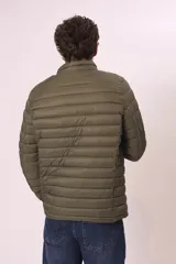 Campera puffer color verde militar, con cuello alto y cierre frontal. Diseño acolchado horizontal.